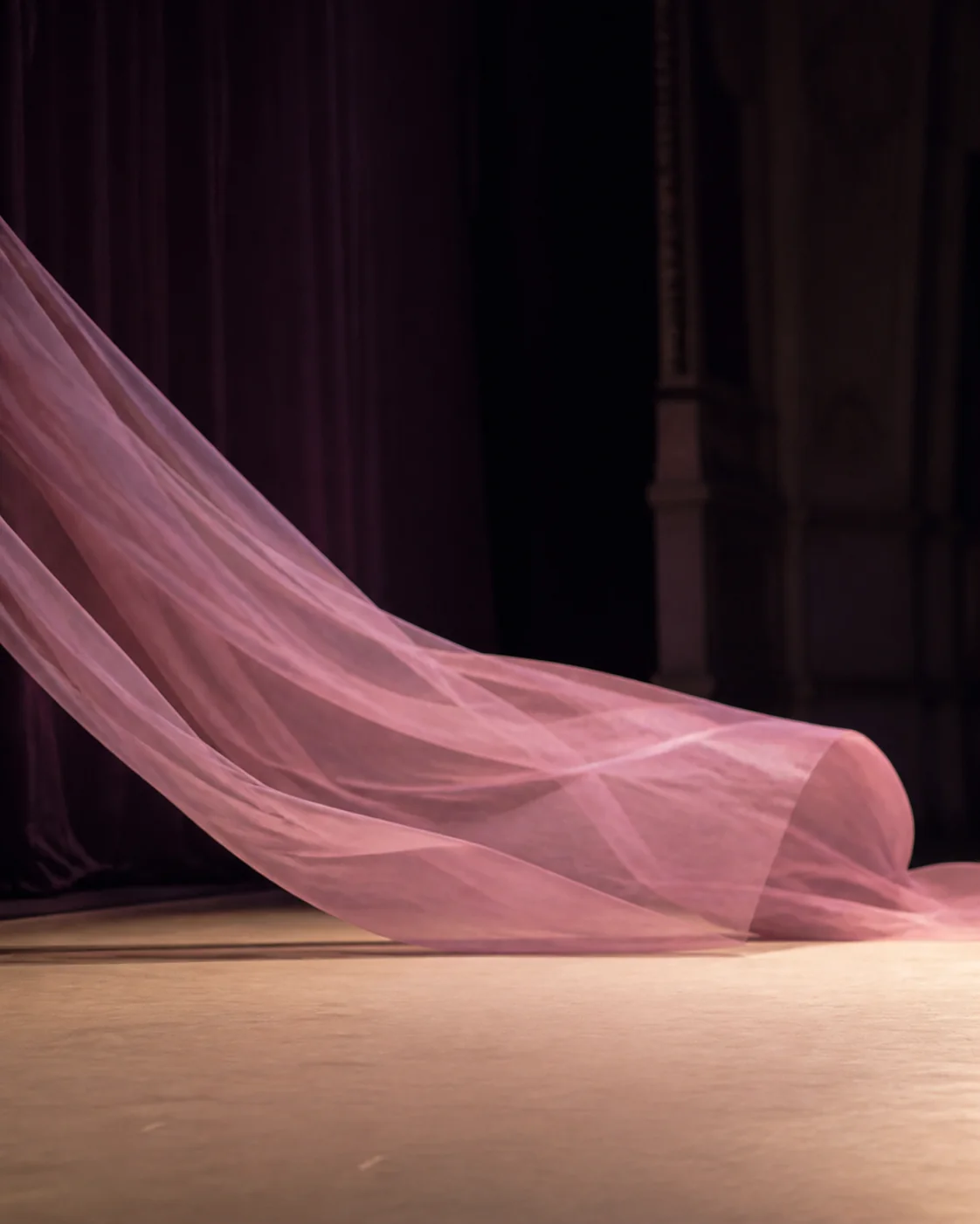 Roséfarbener Bühnenstoff im warmen Licht vor einer Ballettperformance