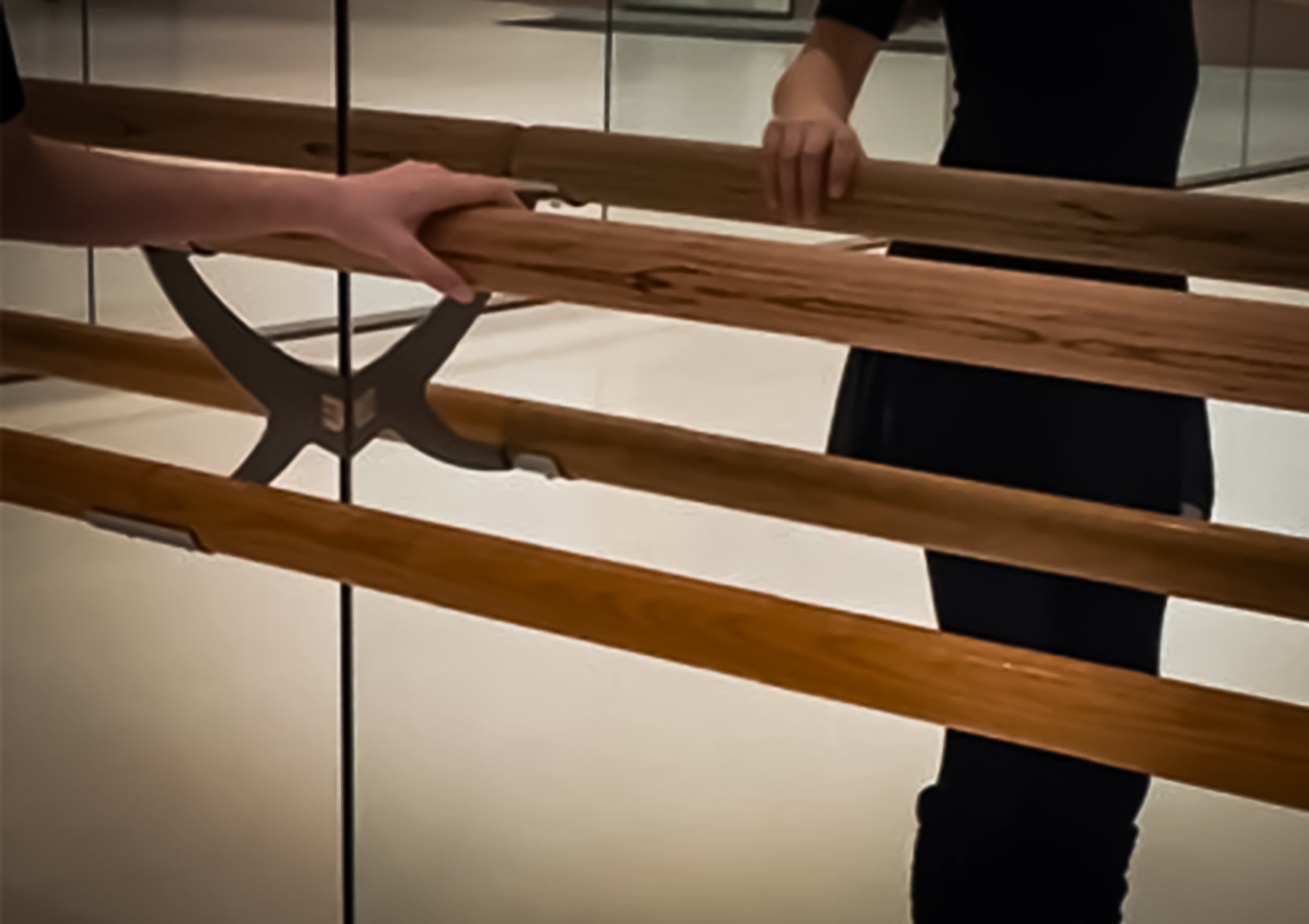 Hand an einer Ballettstange vor der Spiegelwand im Ballettstudio