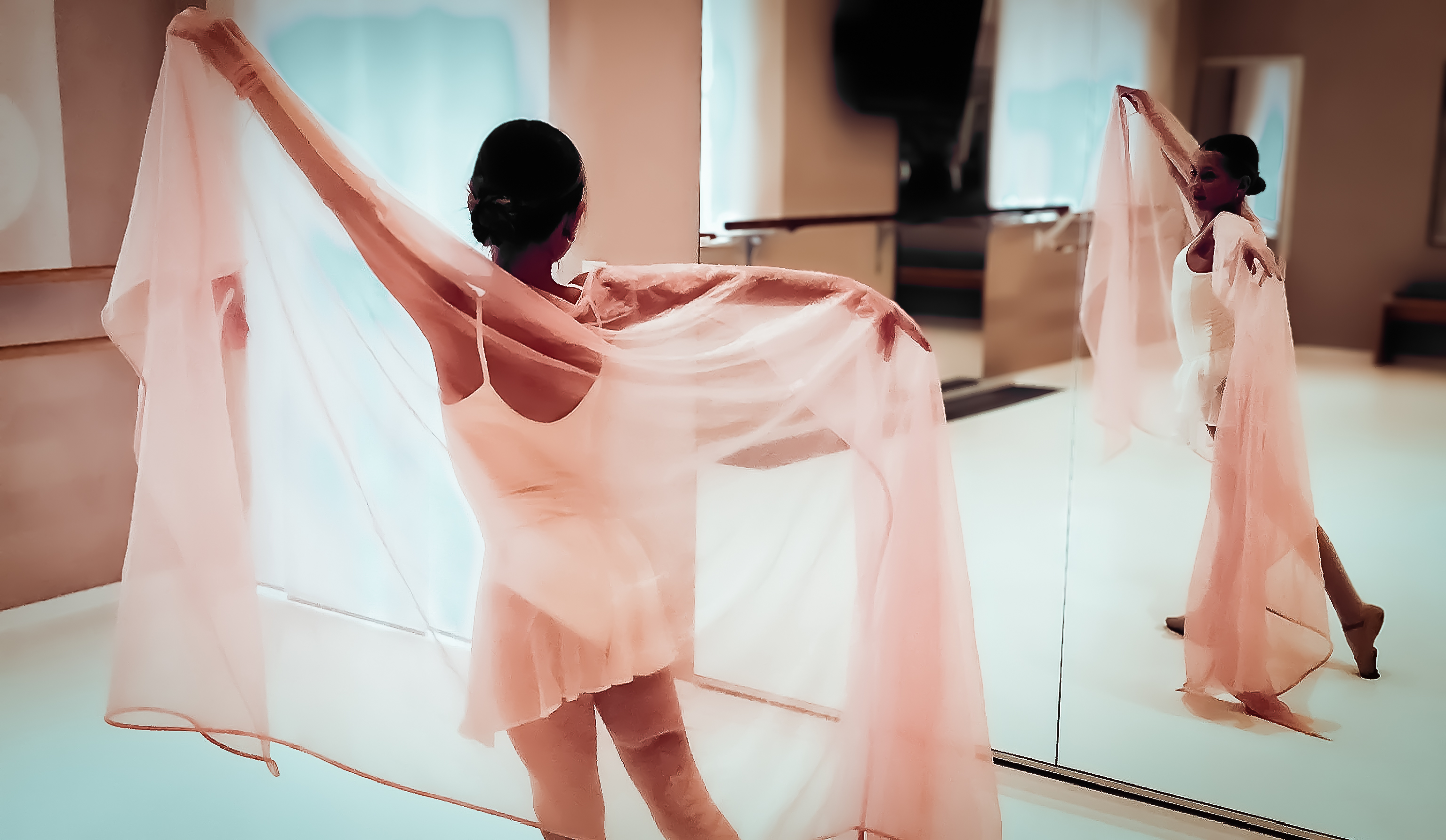 Tänzerin mit roséfarbenem Tuch vor Spiegel und Ballettstange im Studio